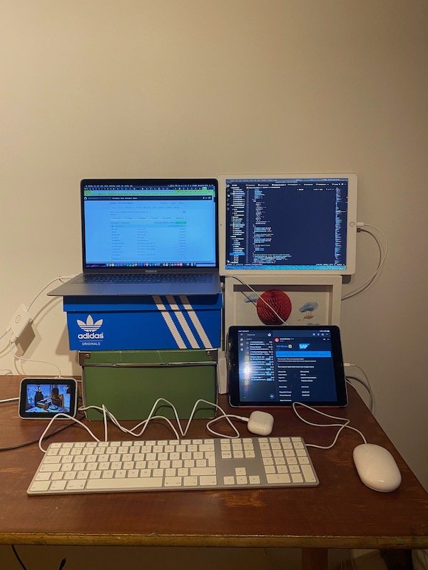 School bench on two chairs. On top of the school bench are shoe boxes with a laptop on top and two iPads surrounding it.